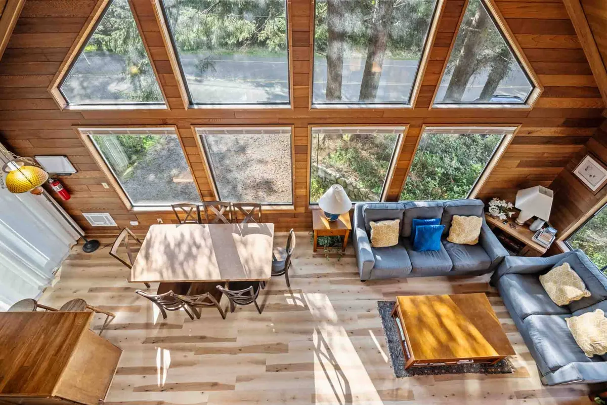 A cozy, inviting dining and living area with large windows that frame the surroundings, allowing natural light to flood the space. The arrangement encourages conversation and shared moments, ideal for friends gathering after adventures or for morning planning sessions before heading into town.
